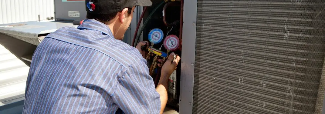 HVAC technician servicing a condenser unit in Upland